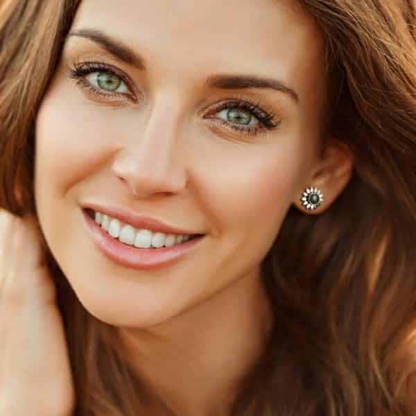 A Woman Smiling While Wearing Silver Labradorite Earrings